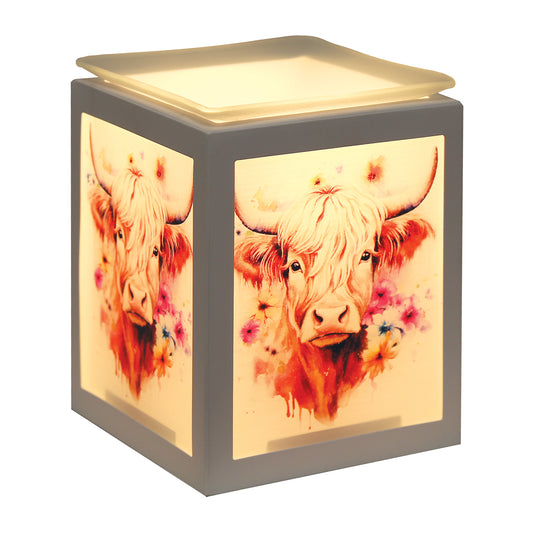 A cube-shaped decorative lamp with a gray frame and a warm glowing cream-colored interior, featuring watercolor-style illustrations of a Highland cow and flowers on the front and side panels.