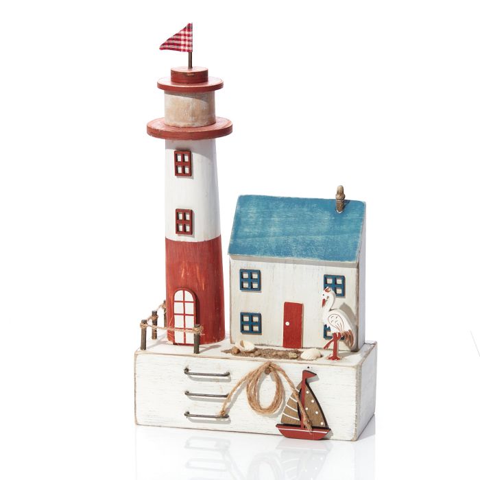 A decorative nautical-themed wooden ornament or figurine featuring a red and white lighthouse, a small blue-roofed house, a white seagull, rope details, and a small sailboat on a white base, photographed on a clean white background.